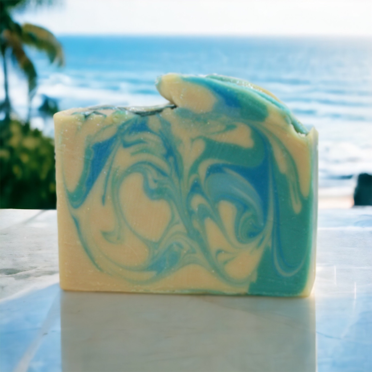 Baja Bloom Bar Soap on a white marble sill with a tropical beach in the background Alpaca Soaps AlpacaSoaps