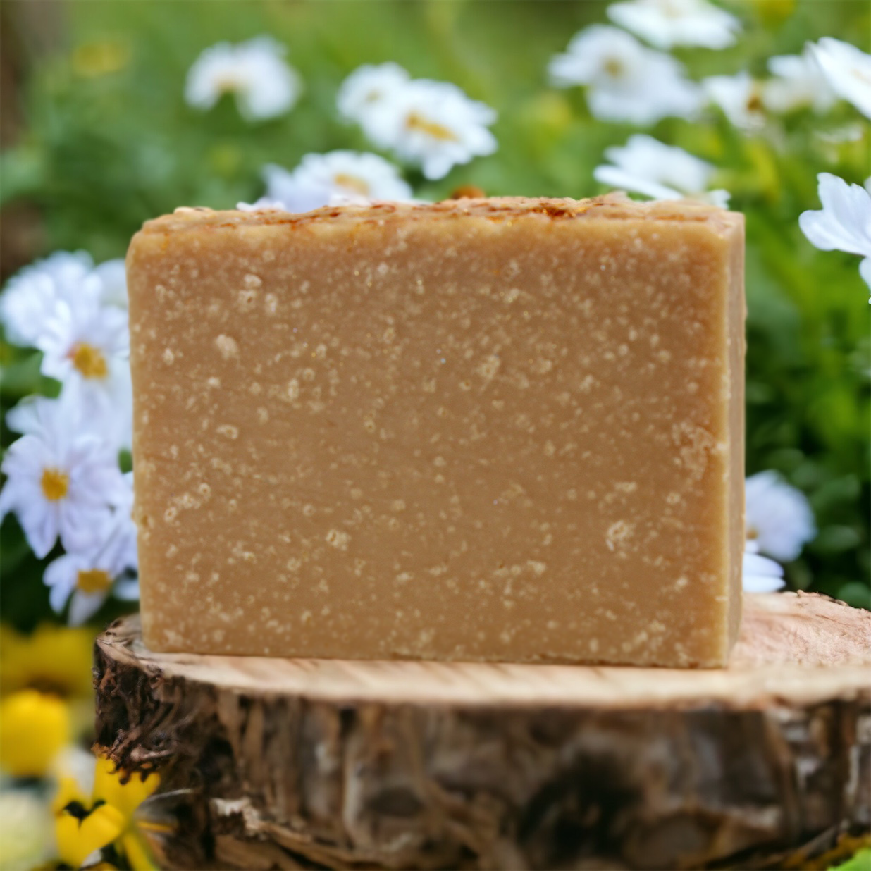 Honey Oatmeal Bar Soap on rustic wood round with flower garden in the background Alpaca Soaps AlpacaSoaps
