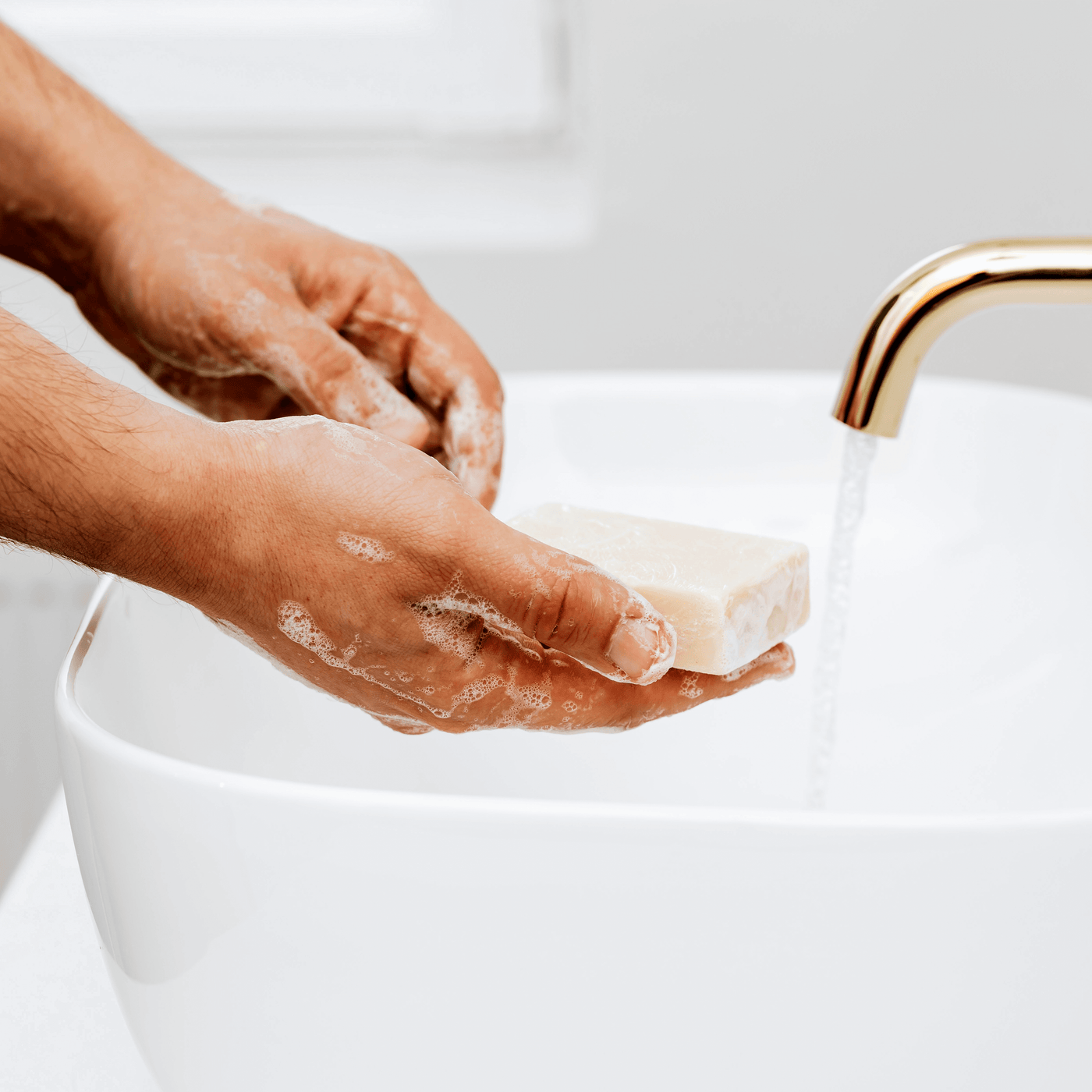 Mans hands. Washing hands with cream-colored handmade soap, white raised basin with a brass faucet. Alpaca Soaps AlpacaSoaps